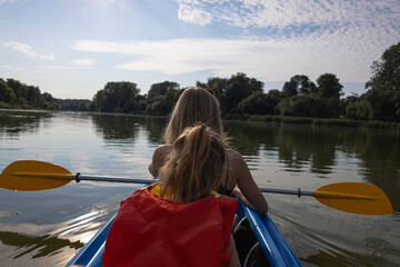 Mother and daughter kayaking on calm river on a sunny summer day, enjoying outdoor adventure and family time together in nature