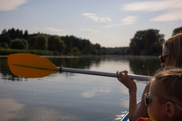 Mother and daughter kayaking on calm river on a sunny summer day, enjoying outdoor adventure and family time together in nature