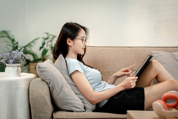 Young woman relaxes home couch using tablet meditation app natural sound therapy