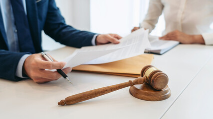 Male lawyer is pointing on legal document to explaining about consultation terms and condition to businesswoman before signing on contract at law firm