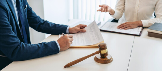 Male lawyer is pointing on legal document to explaining about consultation terms and condition to businesswoman before signing on contract at law firm