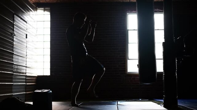 kickboxing work on a bag  man in silhouette, martial arts training cinematic video, gym athletic, strong man