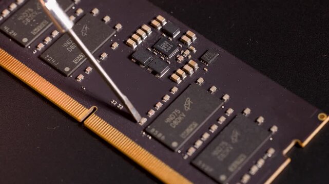 Precision Tool Pointing at Microchip on Electronic Circuit Board