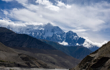 Majestic Himalayan peak emerging from clouds in Mustang, Nepal. Snow-capped mountains for trekking, nature, travel, adventure, and wilderness themes. Geology and tourism use.