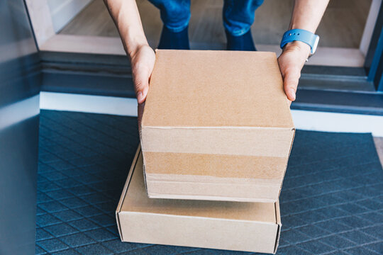 Woman picking up a package left on the porch of her house . Concept for delivery and online shopping