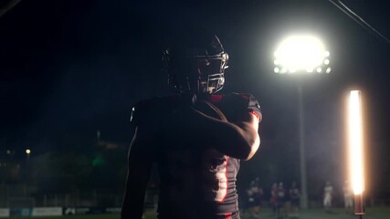 American football player catching a ball at night - Powered by Adobe