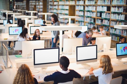 Students in a library with computers, diverse group, studying, learning, library setting, computers, education, diverse students, academic environment. Students in computer class at school.