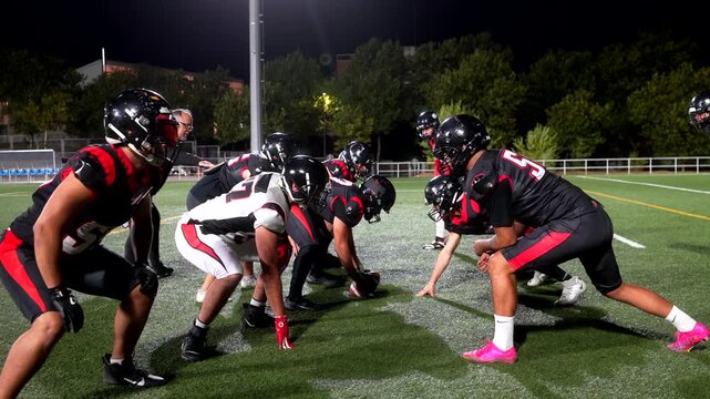 American football players starting a play at night