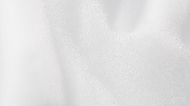 Macro shot of airy white foam texture rotating slowly. Perfect for hair mousse, styling products, beauty, or skincare visuals.
