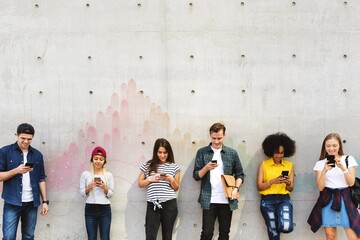 Fototapeta premium Group of young adults outdoors using smartphones together and chilling