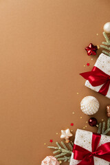 Festive flat lay with gifts, pine branches, and Christmas ornaments in corner layout. Brown vertical background with warm tones.