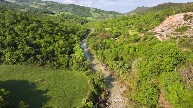 Aerial view of lush green hills, forest and river creating a beautiful landscape, contrasting with the clear sky, Bagno Vignoni, Tuscany, Italy.