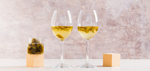 White wine infused with jalapeno slices in glasses on the table web banner