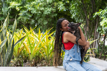 Woman embracing french bulldog in park showing love and affection