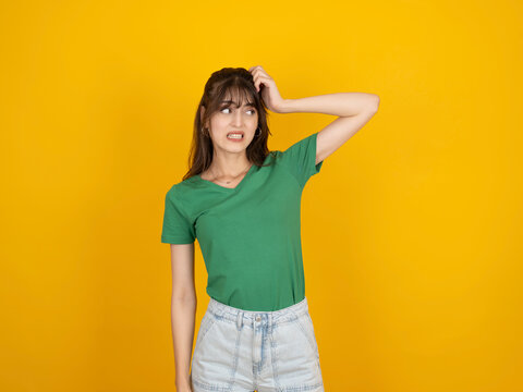 Young mistaken confused woman, portrait of caucasian 20s brunette troubled sad dissatisfied young mistaken confused woman look aside hold scratch head say oops isolated on yellow background.