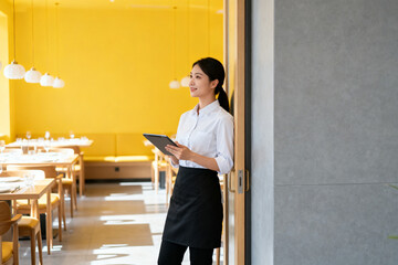 Restaurant server with tablet in yellow dining room
