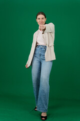 Professional photo collection of young European woman in light blazer with hair tied in ponytail and blue jeans on green chroma key background expressing different emotions and gestures perfect for ad