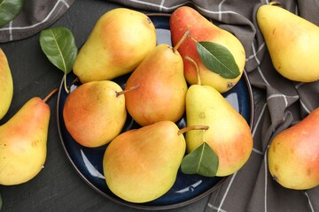Many fresh pears and leaves on black table, flat lay