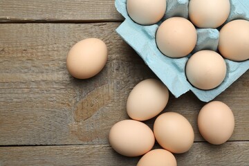 Raw chicken eggs on wooden table, top view. Space for text