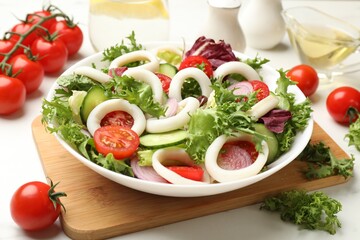 Delicious salad with squid rings and vegetables on white table, closeup
