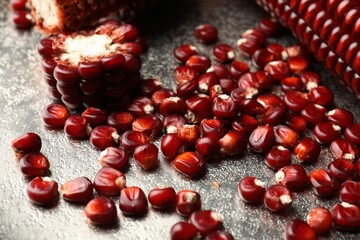 Ripe red corn cobs and kernels on silver textured table, closeup