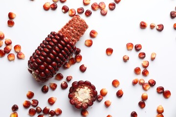 Ripe red corn cob and kernels on white table, flat lay