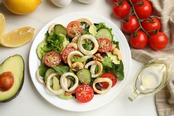 Delicious salad with squid rings and ingredients on white marble table, flat lay