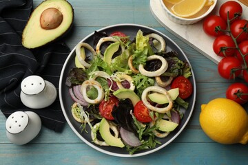 Delicious salad with squid rings and ingredients on light blue wooden table, flat lay