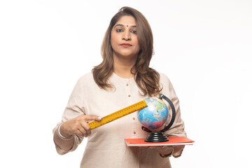 Portrait of Indian confident woman pointing through wooden scale to world globe map against on...
