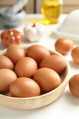 Raw chicken eggs in bowl on white table, closeup