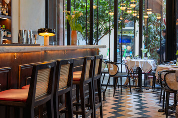 An atmospheric cafe or bar with a vintage style. Dark wooden bar counter and rattan furniture create an elegant, old establishment feel