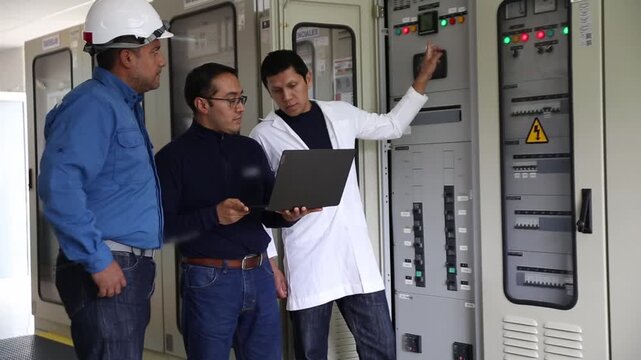 Workers discuss maintenance in the substation control room