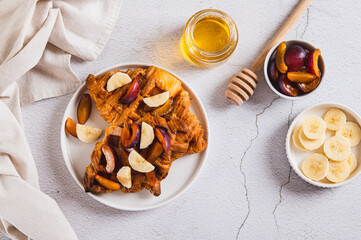 Sweet croffles with banana, plum and honey on a plate on the table top view