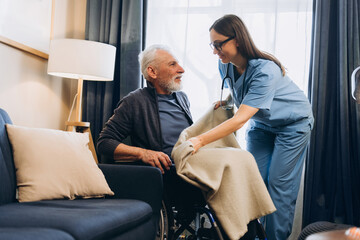 Obraz premium Happy, smiling woman, nurse supporting senior man in wheelchair giving care
