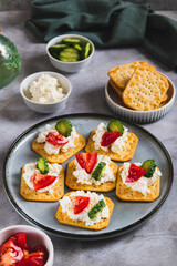 Cottage cheese and vegetables on crackers on a plate on the table vertical view