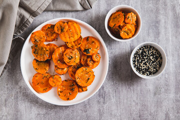 Pieces of fried carrots with garlic and herbs on a plate on the table top view