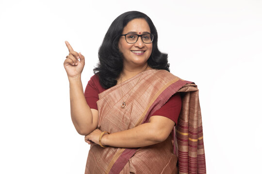 Portraits of Smiling attractive beautiful Indian women pointing to the particular direction or away side.. Wearing traditional colorful saree. Banking sectors white studio background theme
