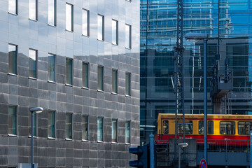 Modern yellow tram passing by glass office buildings in Berlin, representing sustainable urban transportation and connection between architecture and mobility
