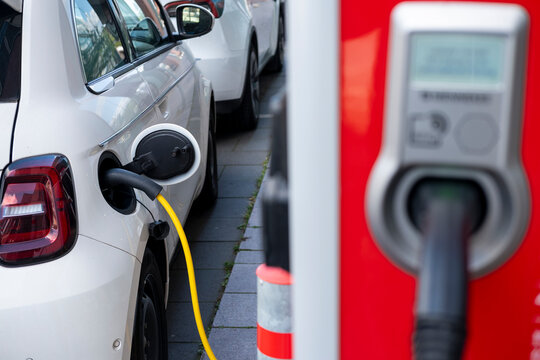 Electric car charging at station with visible cable and plug, representing transition to clean energy and sustainable transportation