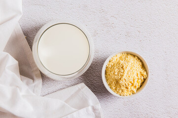 Close up of colostrum powder in a bowl and a drink in a glass on a table top view