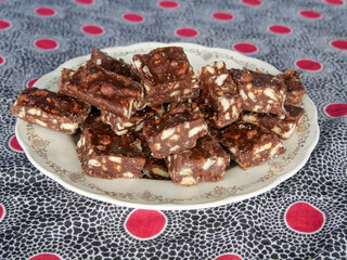 Close-up of blocks of chocolate brownie and biscuit sweets stacked on top of each other on a plate.