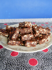 Close-up of blocks of chocolate brownie and biscuit sweets stacked on top of each other on a plate. Vertical image