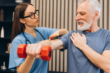 Fototapeta premium Young physical therapist assisting senior man with rehabilitation exercise