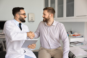 Man doctor and male patient smiling and shaking hands