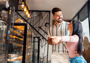 Happy young couple standing in bakery selecting fresh pastries.
