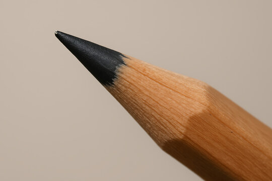 A macro close-up of a sharpened pencil tip, showcasing the fine graphite point and the smooth wooden texture. The neutral background and precise focus emphasize simplicity, craftsmanship, and minimali