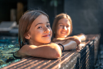 Pool edge look, girl leaning on tiles and smiling. Two friends.