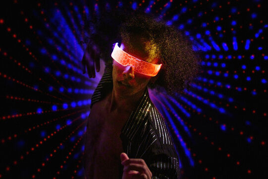 Virtual reality dancer in neon glasses illuminated at futuristic nightclub