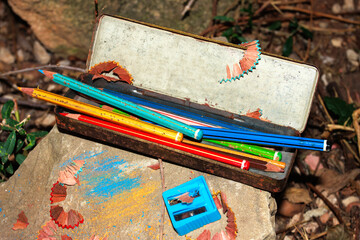 Vintage colored pencils in holder with sharpener and shavings outdoors