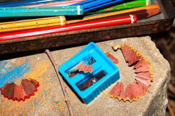 Color pencils and sharpener with shavings on vintage school desk